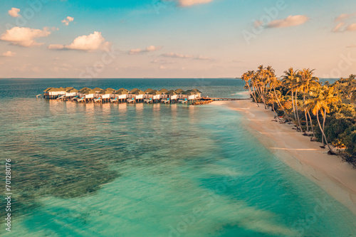 Amazing aerial beach landscape. Beautiful Maldives sunset seascape view. Horizon colorful sea sky clouds over water villa pier pathway. Tranquil drone view island lagoon tourism travel exotic vacation © icemanphotos