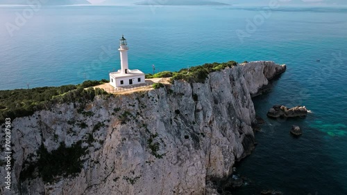 Aerial view of Phare de Akrotiri Lefkada Lighthouse in Cape Doukato. View from above of a white tower on a rocky cliff by the edge of the coast in Lefkada surrounded by emerald-blue waters. photo