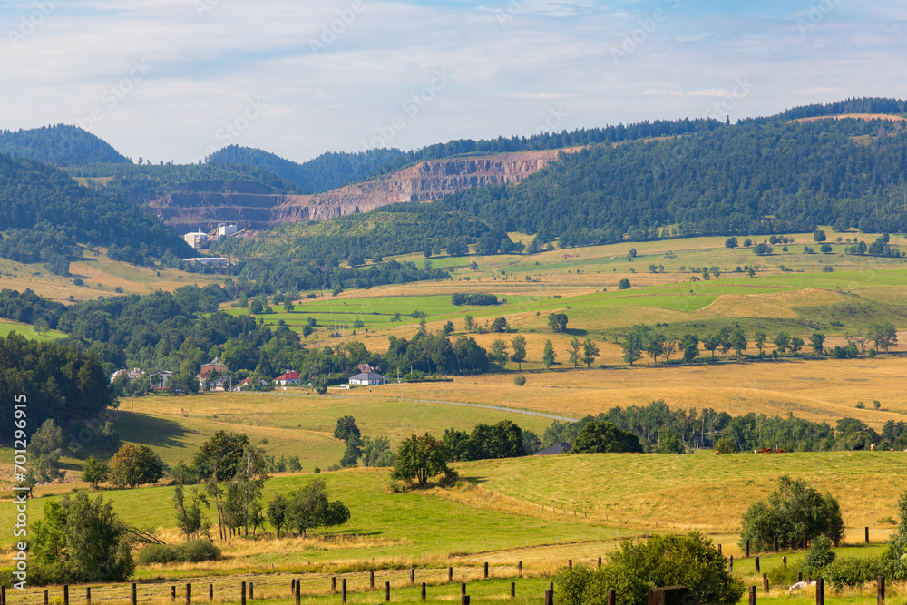 Beautiful landscape of glades and clearing full of fields and trees between it at mountains at sunny cloudy day