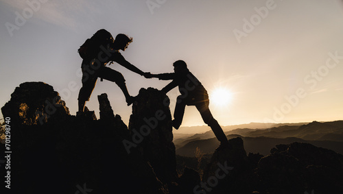 silhouette of Teamwork of three hiker helping each other on top of mountain climbing team. Teamwork friendship hiking help each other trust assistance silhouette in mountains, sunrise.
