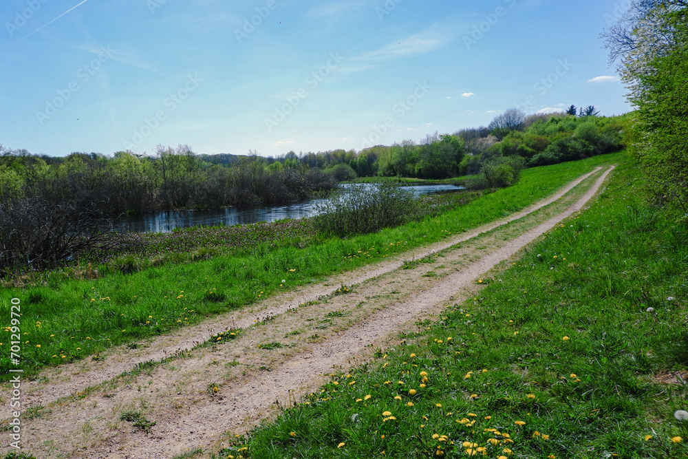Fototapeta premium View of dirt road in countryside near the pond.