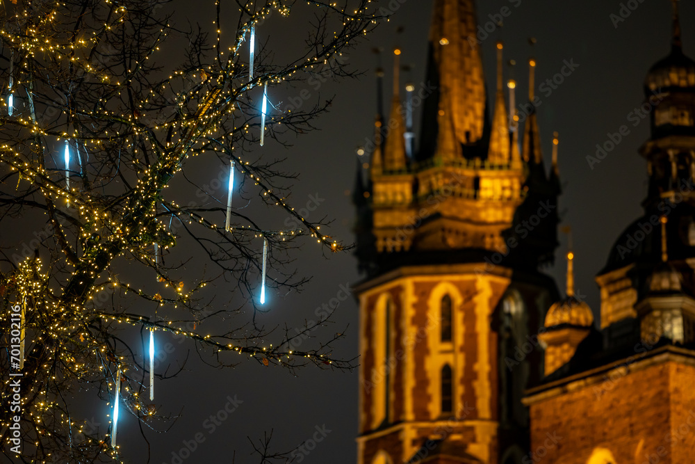The tower of St. Mary's Basilica in Krakow against the background of Christmas decorated trees. Night view of Krakow's Old Town.