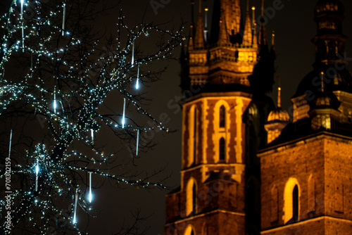 The tower of St. Mary's Basilica in Krakow against the background of Christmas decorated trees. Night view of Krakow's Old Town. photo