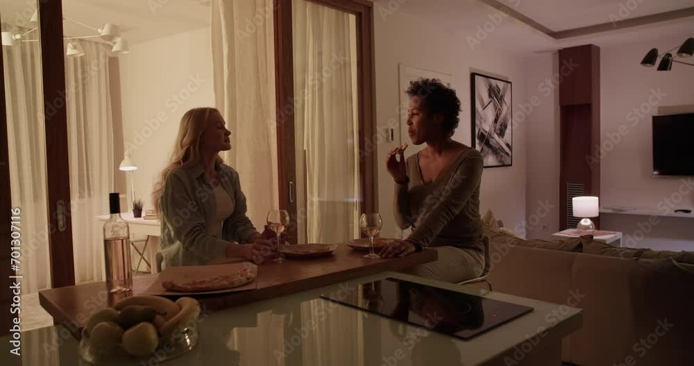 Cheerful multiethnic girlfriends chatting in dark kitchen Cheerful multiethnic girlfriends chatting in dark kitchen