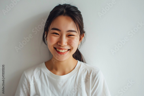 asian woman winking to camera smiling joyful standing white wall