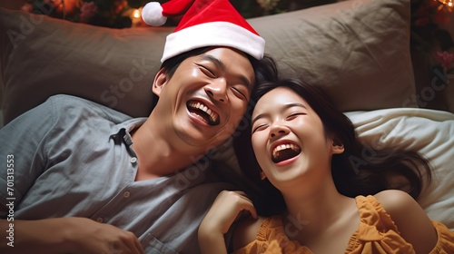 Happy Attractive Young asian Family Portrait Healthy harmony in life family day concept asian family man with Santa hat and woman having good time together. Top view bedroom mattress.