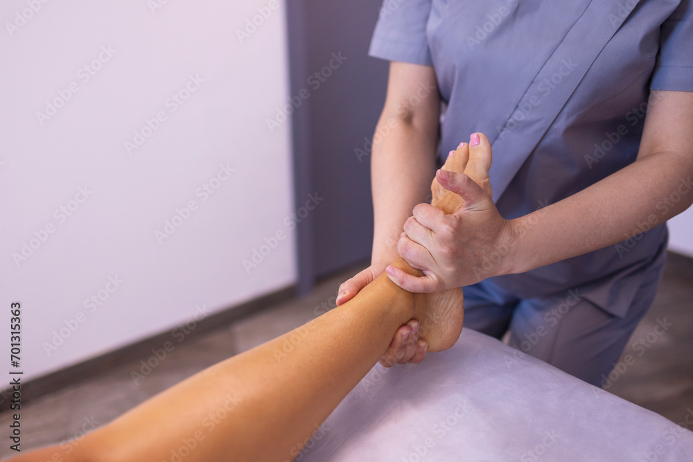 Fototapeta premium Close up of female foot getting gentle massage. Masseuse holds woman leg in her hands.