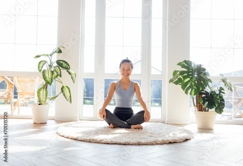 Asian woman does yoga in the living room of her house