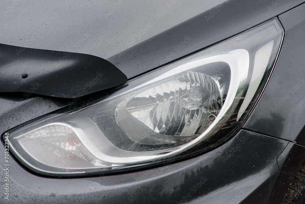 Halogen headlight on a gray car. Close-up.