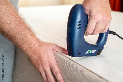 Worker stapling sofa lining with electric staple gun photo