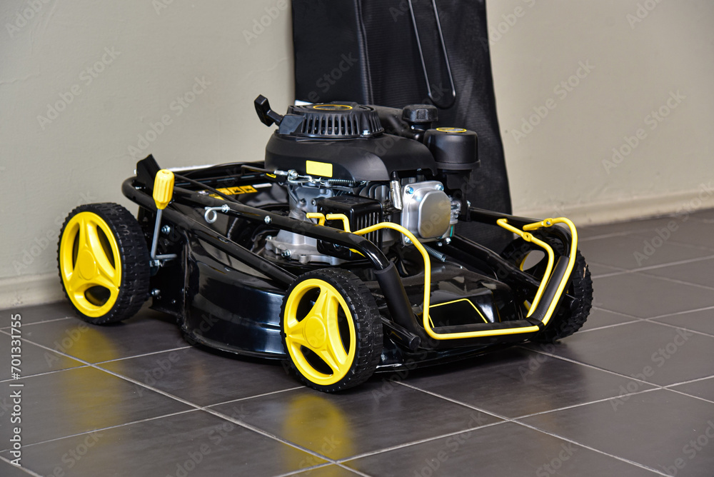 A gasoline lawn mower stands on the floor in the garage.