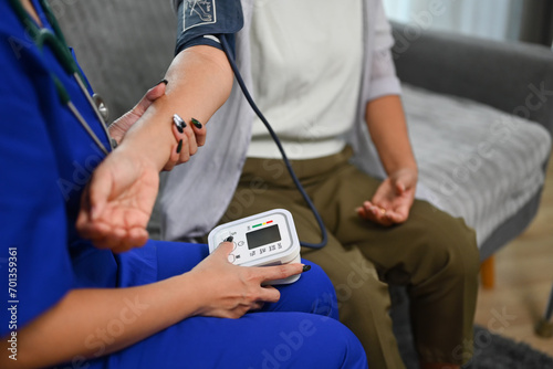 Healthcare worker measuring blood pressure senior woman during home visit. Home health care service concept photo