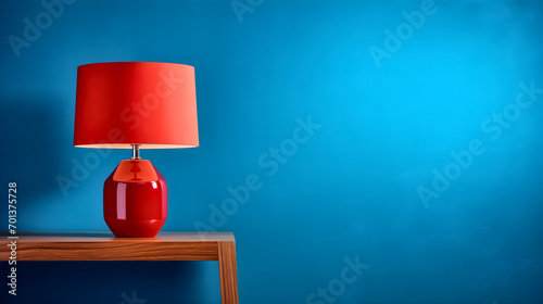 Red lamp placed on a wooden table, in front of the blue room wall. Home interior decoration concept, stylish accessories 