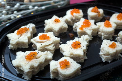 Closeup of appetizers toast with salmon and lumpfish roe in a black plate 	
