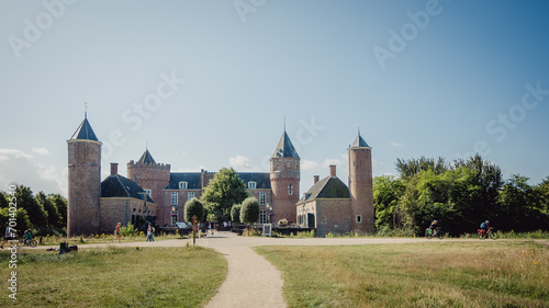 Kasteel (Burg) Westhove - Bikepacking Touristen fahren an der Burg entlang, Domburg, Zeeland, Niederlande photo