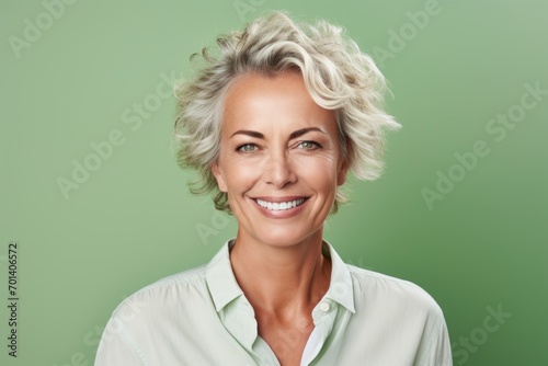 Portrait of happy mature businesswoman with blond hair over green background © MediaRaw