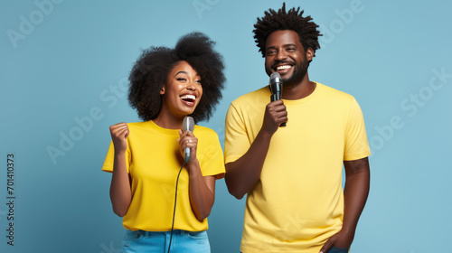 Man and a woman smiling and holding microphones.