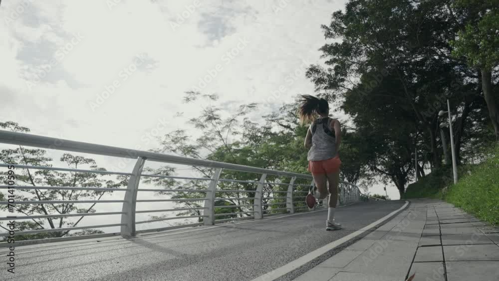 rear view of a young asian woman jogger running outdoors in park rear view of a young asian woman jogger running outdoors in park