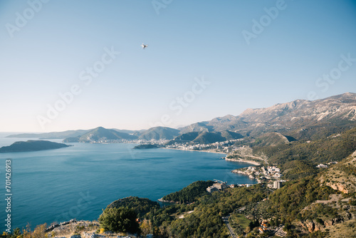 White drone flies on the Bay of Kotor surrounded by green mountains. Montenegro
