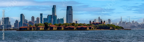 Photograph of Ellis Island, from Liberty Island where the iconic statue of New York (USA) is located and the Big Apple skyline in the background. photo