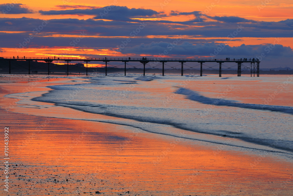 Beautiful light reflecting of a beach with a pier in the background. Saltburn-by-the-sea, North Yorkshire, England, UK.