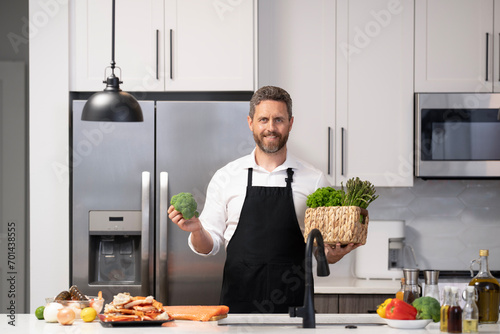 Hispanic man cooking in kitchen. Healthy food for dinner. Man cooking home food. Healthy food  cooking concept. Mature man in apron choose ingredient. Home menu. Whip up a meal