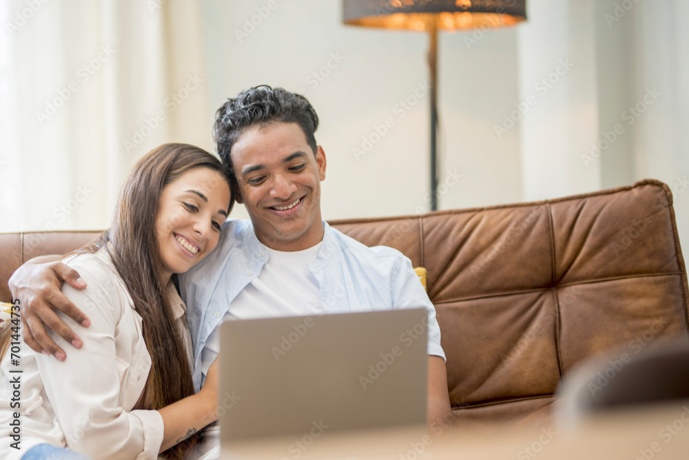 Young couple moving to a new home relaxing sitting on the sofa using computer laptop, smiling happy for moving to new apartment Young couple moving to a new home relaxing sitting on the sofa using computer laptop, smiling happy for moving to new apartment
