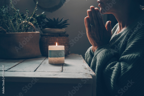 Christian woman kneeling and praying near candles. He seeks guidance in his religious faith and spirituality. Spirit of Christianity and faith in the goodness of God photo