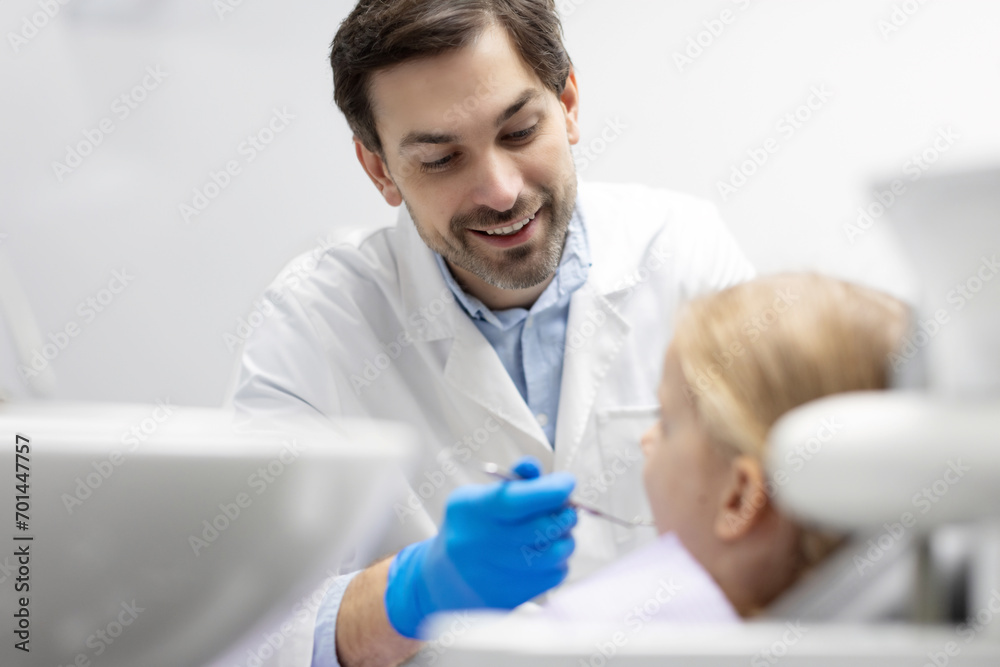 Cheerful male dentist checking the teeth of girl teenager, preparing for dental treatment in clinic Cheerful male dentist checking the teeth of girl teenager, preparing for dental treatment in clinic