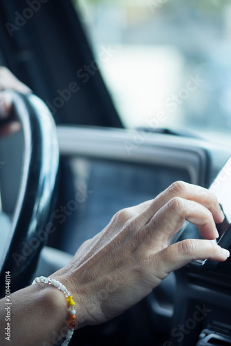 Close up of woman hand setting the gps online navigator on the phone while drive - people and travel with technology help to find the way - using app application on mobile celluar inside the car