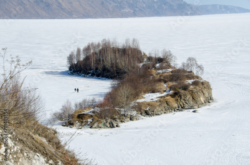 Shaman Cape in Siberia, near Sludanka station. Snowy frozen Baikal around it. photo