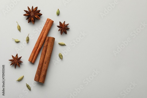 Fototapeta Naklejka Na Ścianę i Meble -  Cinnamon sticks, star anise and cardamom pods on light grey background, flat lay. Space for text