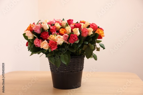 Bouquet of beautiful roses on wooden table against beige background