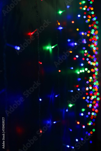 Strings of blue, red and green holiday lights in the dark as a background. Photo in perspective with selective focus