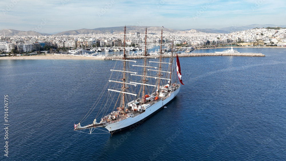 Aerial drone photo of beautiful 3 mast barque or barc type classic sailing wooden boat with huge waving flag anchored near port of Piraeus, Attica, Greece