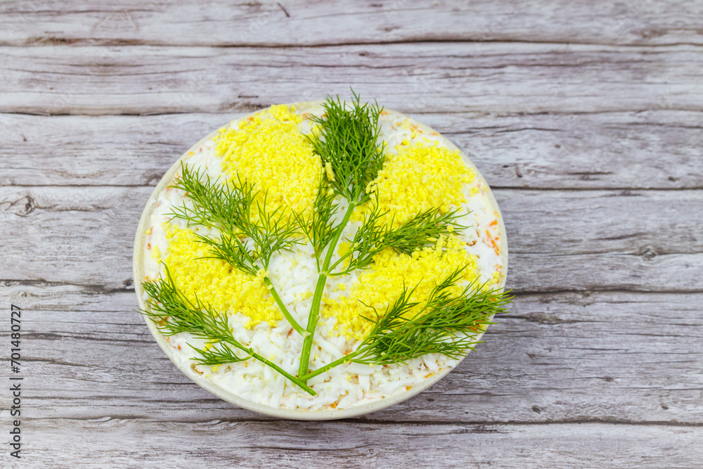 Φωτογραφία Traditional russian layered salad Mimosa decorated with sprigs of mimosa (made of eggs yolk and dill) on wooden table