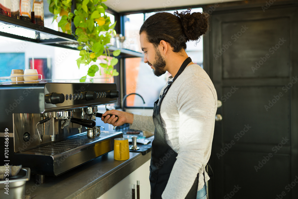 Handsome hispanic man preparing coffee in the espresso machine Handsome hispanic man preparing coffee in the espresso machine