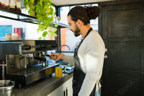 Handsome hispanic man preparing coffee in the espresso machine