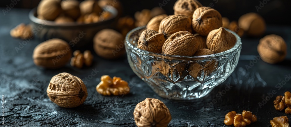 walnuts in a clear glass bowl and scattered on a black table selective focus. Creative Banner. Copyspace image walnuts in a clear glass bowl and scattered on a black table selective focus. Creative Banner. Copyspace image