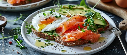 Toast with salmon poached egg and avocado on a white plate Poached egg with salmon and guacamole on rye bread. Creative Banner. Copyspace image