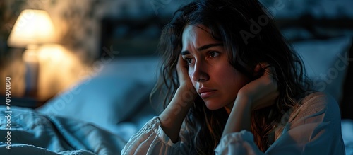 young beautiful hispanic woman at home bedroom lying in bed late at night trying to sleep suffering insomnia sleeping disorder or scared on nightmares looking sad worried and stressed photo