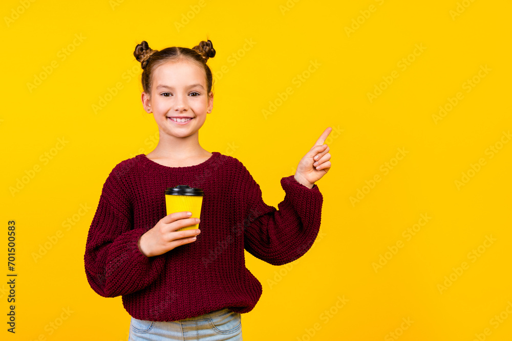 Portrait of small positive person beaming smile hold coffee cup indicate finger empty space isolated on yellow color background Portrait of small positive person beaming smile hold coffee cup indicate finger empty space isolated on yellow color background