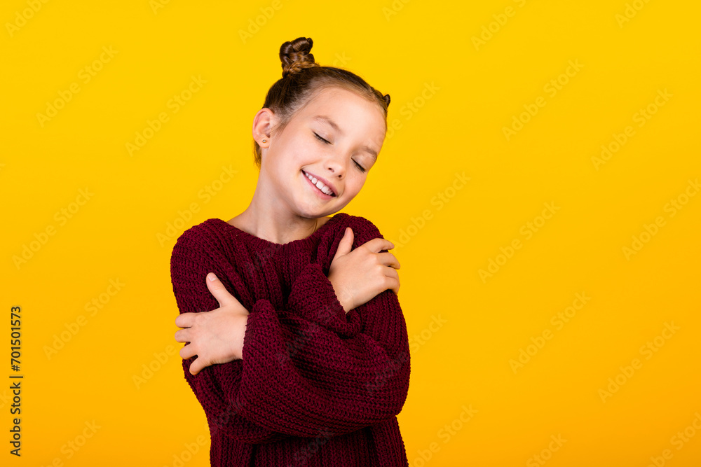 Portrait of little charming cheerful girl closed eyes hands embrace shoulders empty space isolated on yellow color background