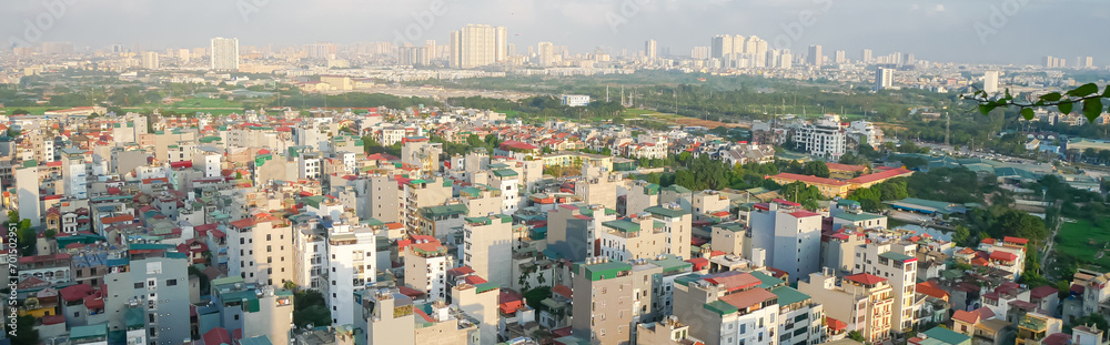 Panorama dense of multistory residential houses with caged balcony and row of high-rise apartment tower complex in background at Van Quan, Ha Dong District, Southwest of Hanoi, Vietnam
