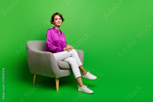 Photo of adorable stunning lady in trendy clothes sitting comfort chair empty space isolated on green color background photo