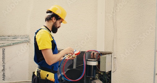 Adept repairman calibrating pressure measurement device during comissioned air conditioner troubleshooting. Proficient worker reading vacuum pressure of condenser liquids and gases photo