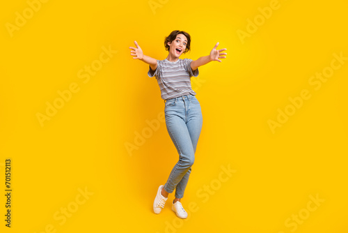 Full size portrait of astonished cheerful girl raise opened hands welcome you isolated on yellow color background photo
