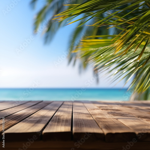 A wooden table on an exotic beach  palm leaves on a blurry background  with the blue ocean in the background. Holiday atmosphere
