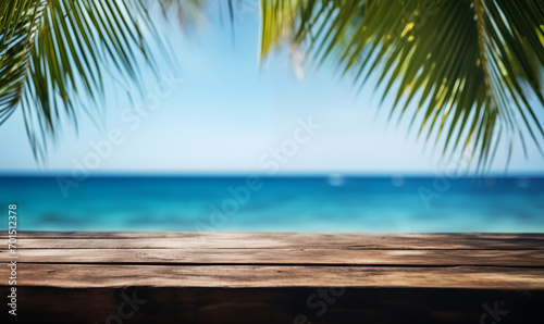 A wooden table on an exotic beach  palm leaves on a blurry background  with the blue ocean in the background. Holiday atmosphere