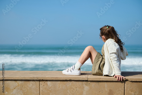 Adorable little kid girl breathing fresh air and enjoying beautiful view of waves pounding on the Atlantic shore